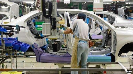 A Toyota Motor employee fixes the main battery of the hybrid system on an assembly line for the Corolla Axio