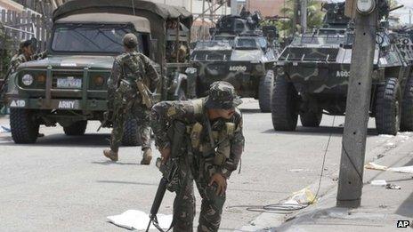 Government troopers, backed by armoured personnel carriers, position themselves at an intersection at the southern port city of Zamboanga in southern Philippines Wednesday, 11 September 2013