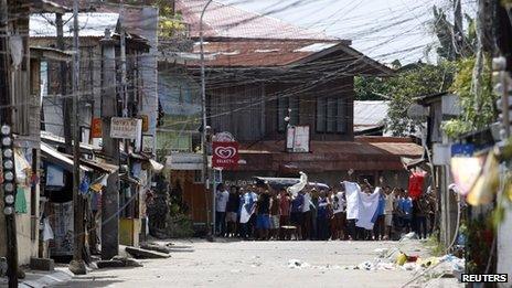 Residents believed to be hostages and used as human shields of Moro National Liberation Front rebels wave white cloth and shout to the government soldiers to "stop firing" while standing in the rebels' positions in downtown Zamboanga city, in southern Philippines 11 September 2013