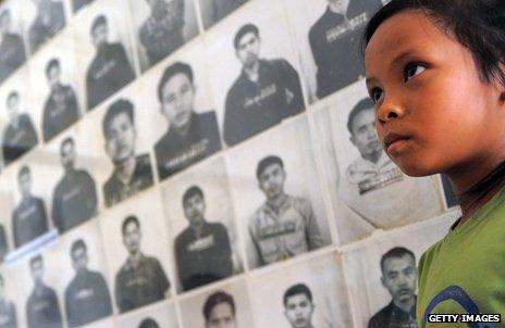 Child looks at photos of Khmer Rouge torture victims