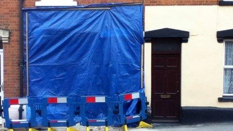 Exterior of the house with much of the ground floor covered with a blue sheet