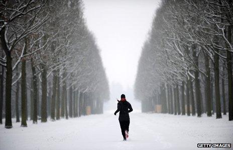 Jogger runs through snowy forest