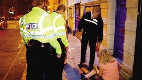 A woman sitting on the floor as three police officers stand by