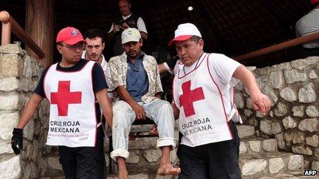 Mexican Red Cross volunteers carry a man during floods in Acapulco on 17 September, 2013