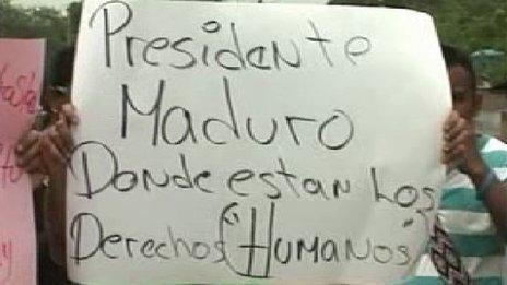 A protesters holds up a sign saying "President Maduro: Where are the human rights?"