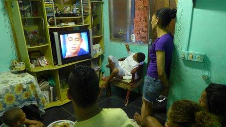 The Silva family watches as Amarildo Silva's son appears on TV