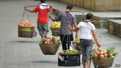 This picture taken on 8 August 2013 shows a vegetable vendors carrying their produce to sell in China"s southwest metropolis of Chongqing