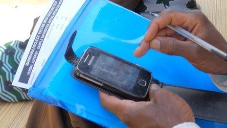 Hands holding a smartphone and papers