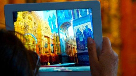 A woman uses a tablet computer to photograph inside a church