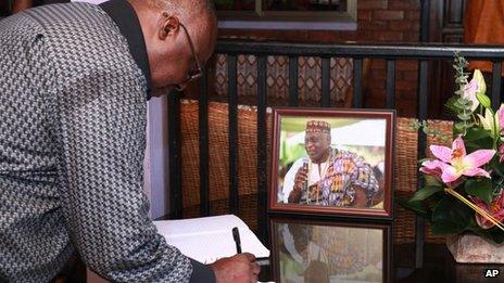 A mourner signs condolences book for Ghanaian poet, professor, and former ambassador Kofi Awoonor, seen in the framed photograph, at his residence in Accra, Ghana, Monday, 23 September 2013