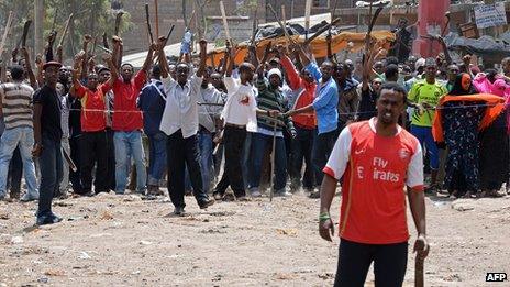 Somali youths armed with machetes and wooden planks shout at Kenyan residents in the somali district of Eastleigh in Nairobi on November 19, 2012.