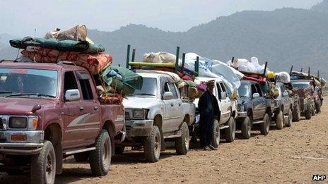 An Internally Displaced Person stands alongside a convoy of vehicles prior to the start of the journey to their home town after an army operation against militants was completed at the Kurram Agency, in Parachamkani on June 29, 2013.