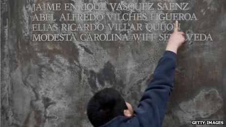 A child points to names on a memorial honouring those killed or disappeared under military rule in Chile on 11 September 2013