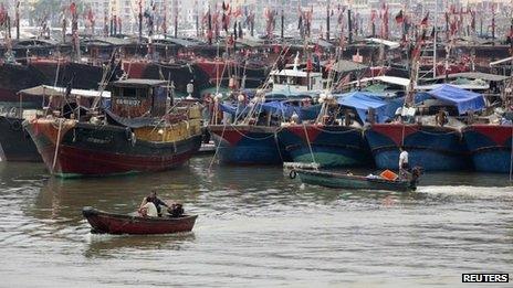 Fishermen drive a boat next to fishing ships docked at a port to shelter from Typhoon Wutip in Sanya, Hainan province, 29 September 2013