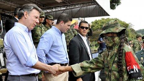 Colombian President Juan Manuel Santos (left) shakes hands with a member of the ELN guerrilla who has defected at a military base on 16 July 2013