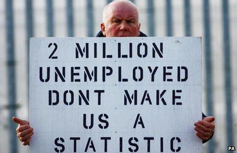 A man holding a sign saying "2 million unemployed - don't make us a statistic"