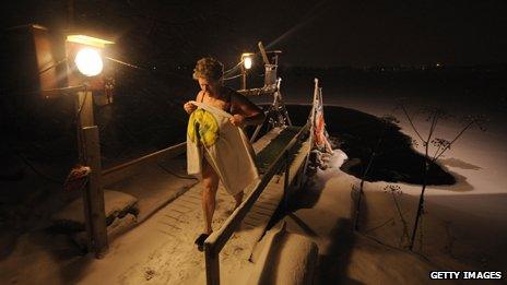 Finnish woman emerges from a frozen lake to return to the sauna