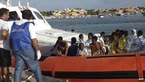 Rescued migrants arrive onboard a coastguard vessel at the harbour of Lampedusa