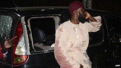 A man who survived the drive-by shooting of Muslim cleric Sheikh Ibrahim Ismail stands next to a bullet-riddled car on the Mombasa-Malindi highway late on 3 October 2013