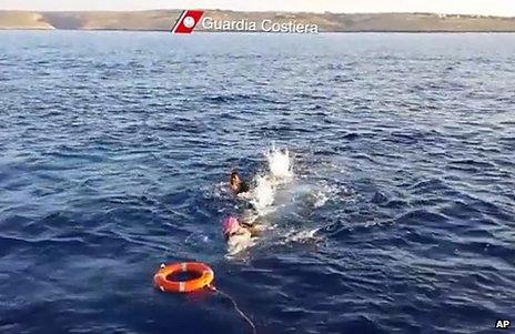 Migrants swim towards a life belt thrown by Italian coast guards, 3 October