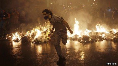 A demonstrator from the group called Black Bloc runs outside the Municipal Assembly during a protest supporting a teachers" strike in Rio de Janeiro