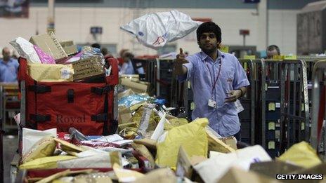 A person throwing a parcel in a Royal Mail sorting office