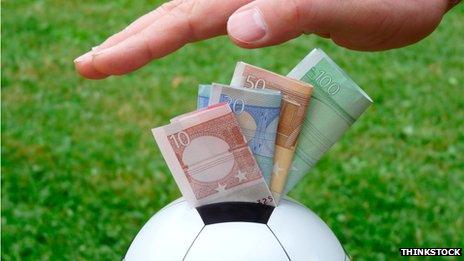 Hand pushing money into a football