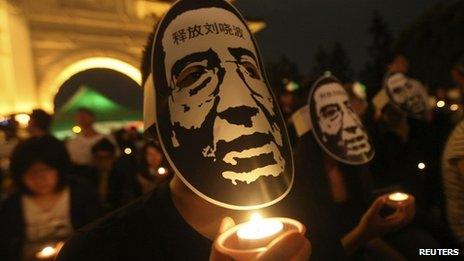 Activists wearing masks of China's jailed Nobel laureate Liu Xiaobo hold candles during a night vigil in Taipei