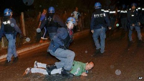 A policeman in riot gear subdues a man during a protest outside the Society of St Pius X headquarters, a schismatic Catholic group, where the funeral of former Nazi war-criminal Erich Priebke was scheduled to take place in Albano Laziale, in the outskirts of Rome, Tuesday, Oct. 15, 2013