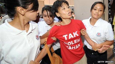 A woman is led away by Singapore police