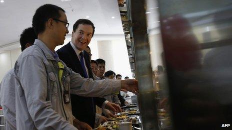 George Osborne talks with workers as they collect food at a canteen near Taishan (17 Oct 2013)