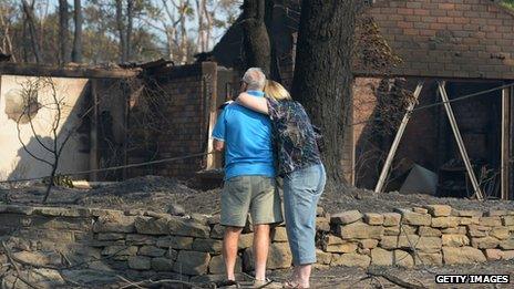 A couple look at a house burnt out by bushfires in Winmalee in Sydney's Blue Mountains on October 18, 2013