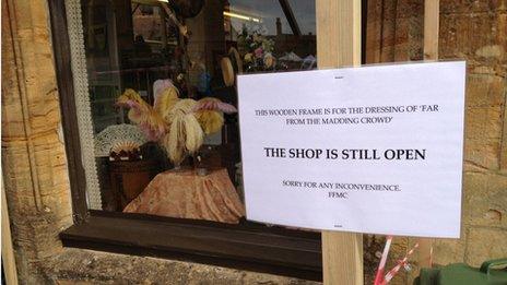 A sign ahead of filming in Sherborne outside Sue Ryder Care charity shop which has had its window display transformed