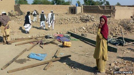 Villagers stand in rubble of a house