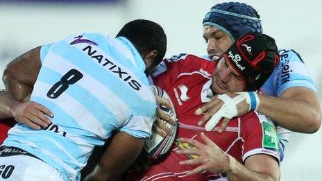 George Earle of Scarlets is tackled by Sakiusa Matadigo of Racing Metro 92 and Luc Ducalcon