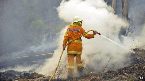 A New South Wales Rural Fire Service volunteer puts out a spot fire in Bell on 20 October 2013