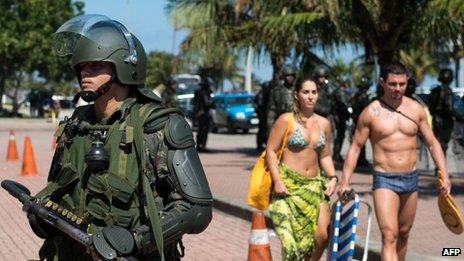 A couple walks past a an officer standing guard in front of the hotel where Brazil's National Petroleum Agency will auction drilling rights to the Libra oil field on 20 October 2013