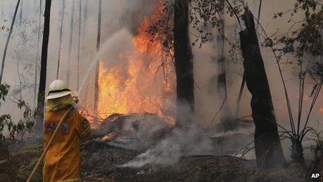 A fire fighter works to control flames near houses in Bilpin, Australia, 22 October 2013
