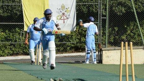 Vatican seminarians play cricket in front of the Vatican flag