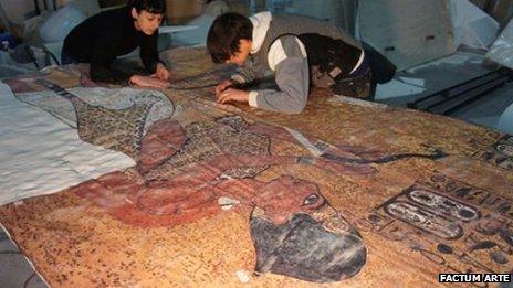 Two people working on the copy of the tomb walls