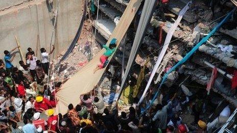 A collapsed building with people climbing fabric