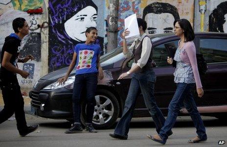 A woman covers her face as she walks past two youths near Tahrir Square in Cairo (9 May 2013)