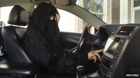 A Saudi woman wearing a burka drives a car