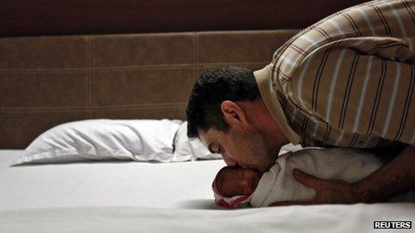 British father kisses his new baby, carried by a surrogate mother in India