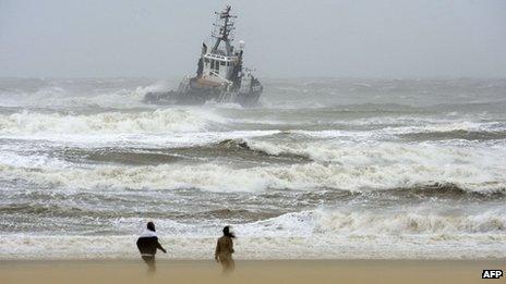 People watch a boat from the shore as a storm passes over the beach in Scheveningen