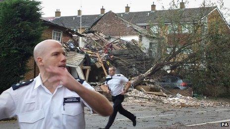 Two police officers rush to secure a residential area after a suspected gas explosion