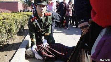 A paramilitary policeman detains a woman who threw papers believed to be her petition papers near the main entrance of the Forbidden City. where the car crash happened, in Beijing, China, 29 October 2013