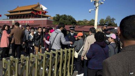 Chinese security personnel direct tourists visiting Tiananmen Gate close to the site of Monday's incident where a car ploughed through a crowd before it crashed and burned in Beijing, China, 29 October 2013