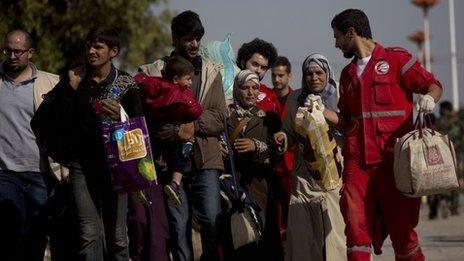 People walk from the rebel-held suburb of Muadhamiya to government-held territory, helped by aid workers