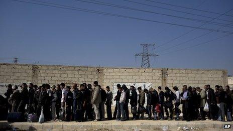 Men wait to be searched by the Syrian military